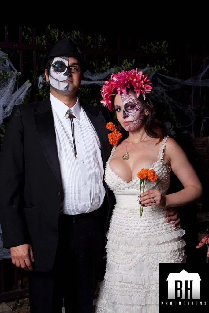 Two people in formal clothing with black and white skeletal face paint.