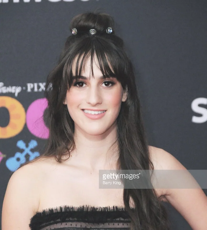Red carpet close-up with a fringe, half-up dark hair and a black strapless dress.