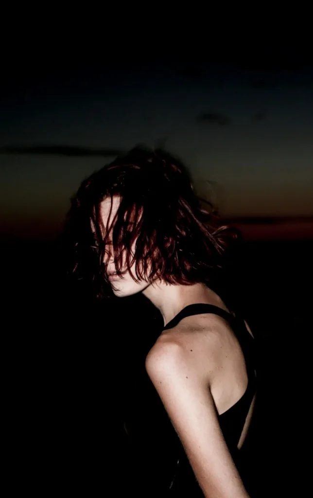 Low-light profile portrait with short dark hair against a dusk sky.